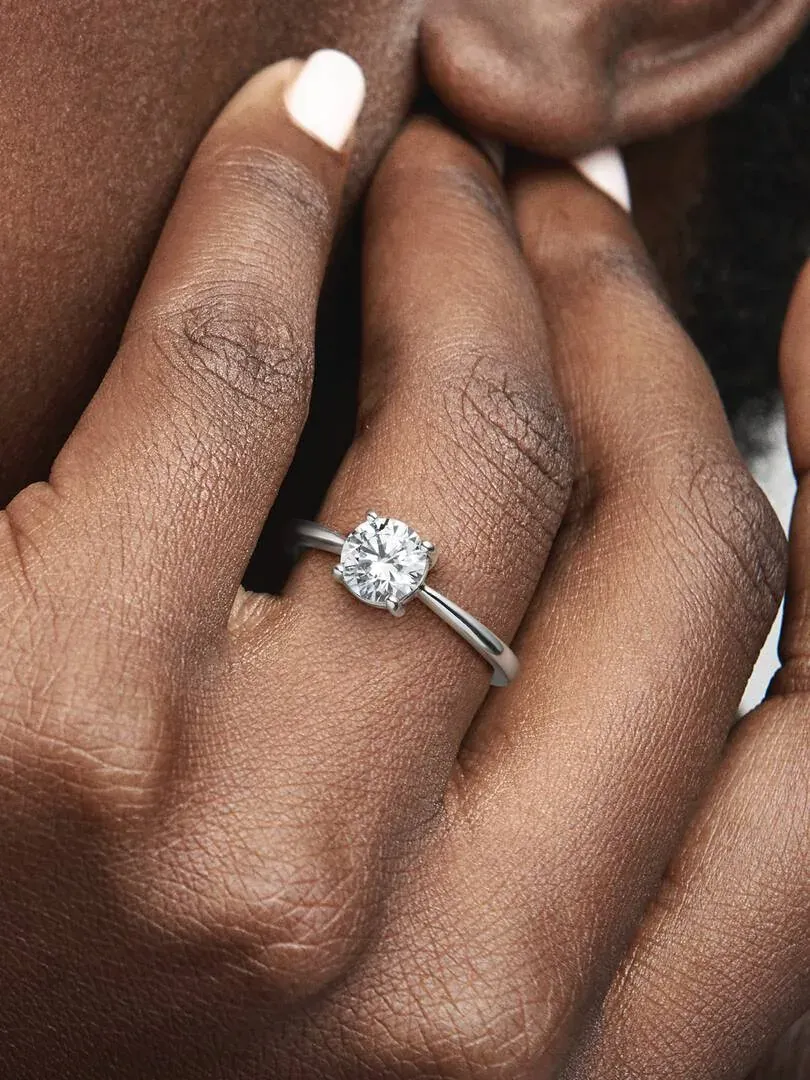 Close-up of the solitaire ring with cubic zirconia on a finger, side view on skin.