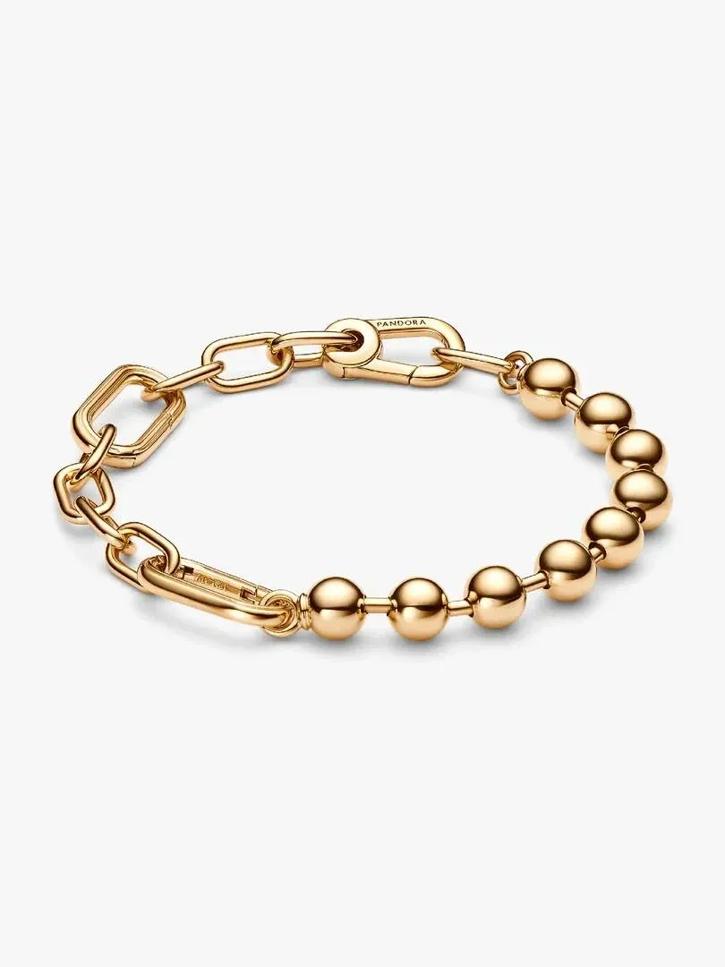 Pulsera de eslabones y esferas doradas dispuesta en círculo, vista desde un ángulo superior sobre fondo blanco.