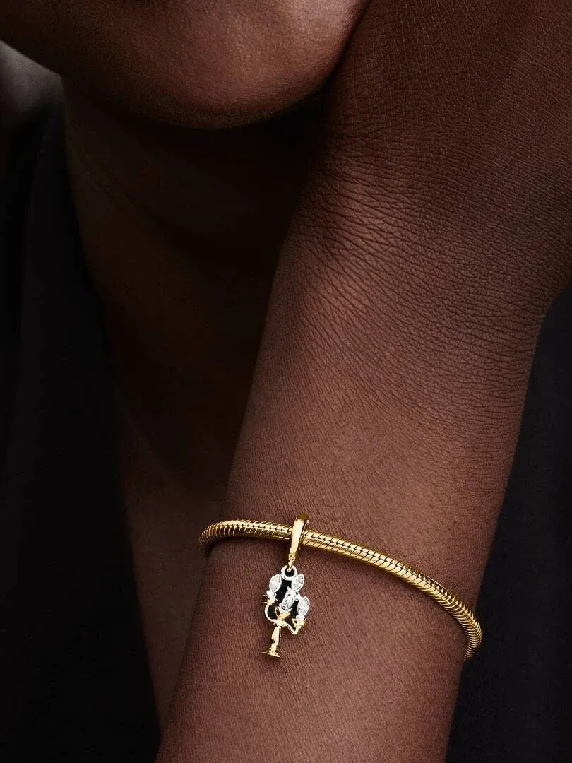 Primer plano del charm colgante en una muñeca, toma lateral con fondo oscuro desenfocado.