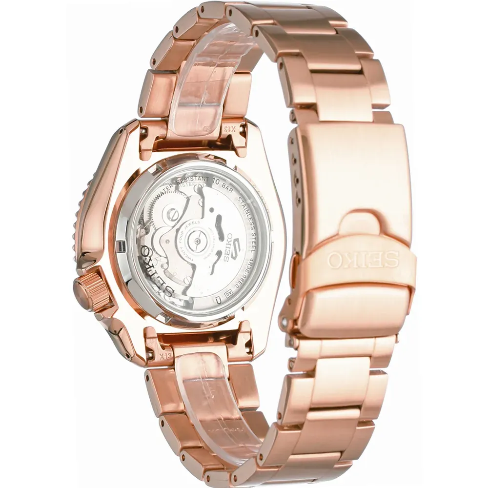 Vista posterior del reloj en tono oro rosa sobre fondo blanco, con tapa trasera transparente y detalle del cierre.