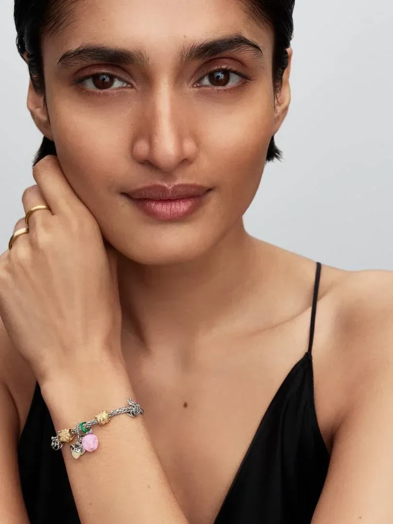 Pulsera con charms de colores en la muñeca de una modelo, toma frontal sobre fondo neutro.