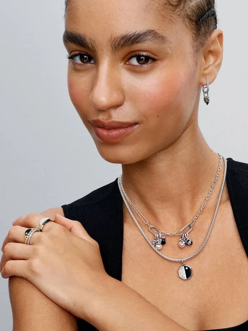 Nahaufnahme eines Models mit der Doppelgelenkkette und passenden Ohrringen vor neutralem Hintergrund.