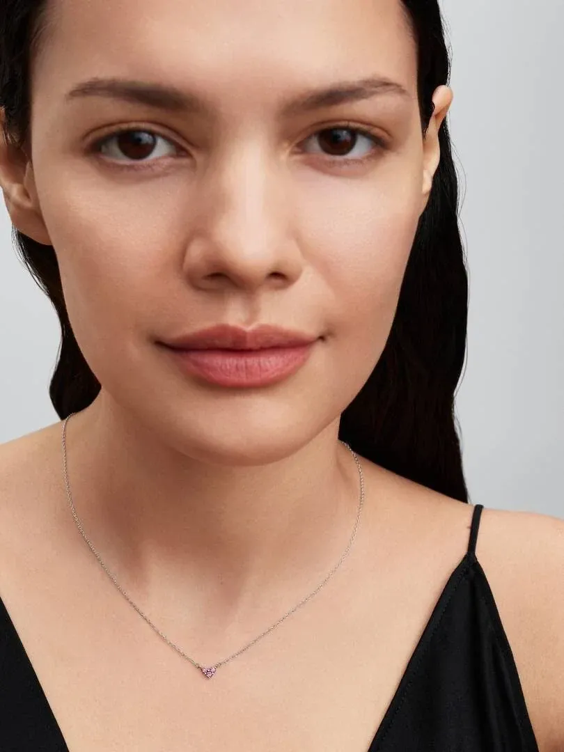 Close-up of the pink heart pendant necklace on a model's neck, neutral background.