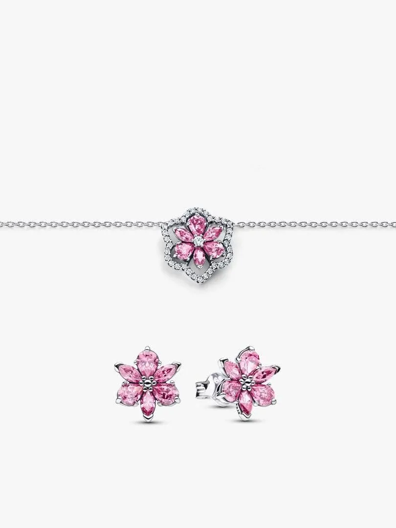 Collar y pendientes de flor rosa sobre fondo blanco, vista frontal con detalle de las circonitas.