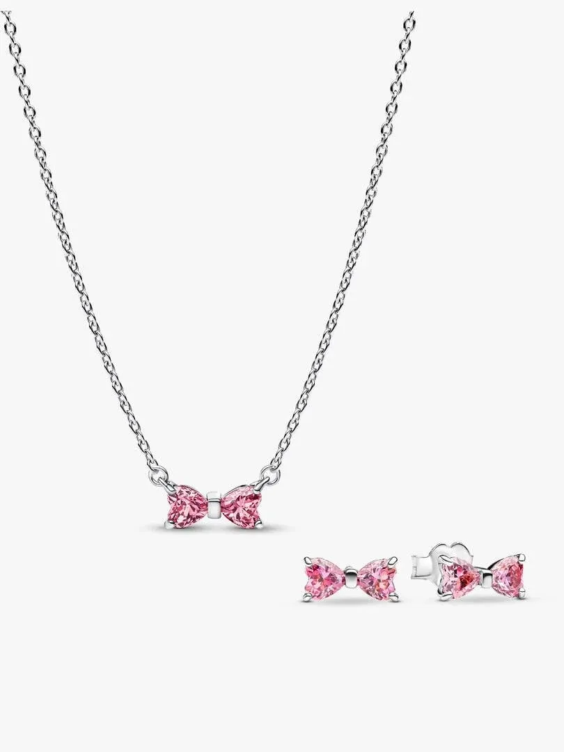 Conjunto de collar y pendientes con lazos rosas sobre fondo blanco, vista frontal con cadena extendida.