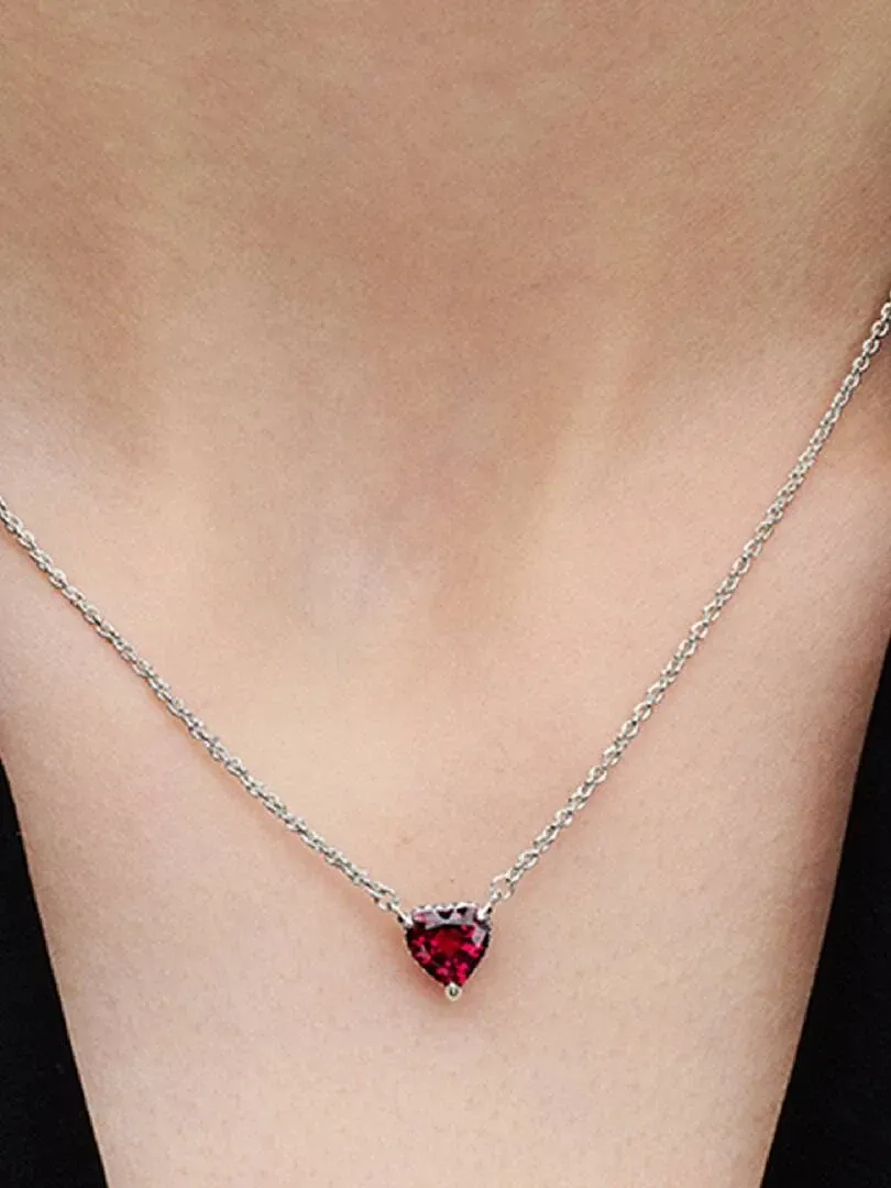Gros plan du collier avec pendentif cœur rouge porté sur le cou d'un mannequin, vue de face.
