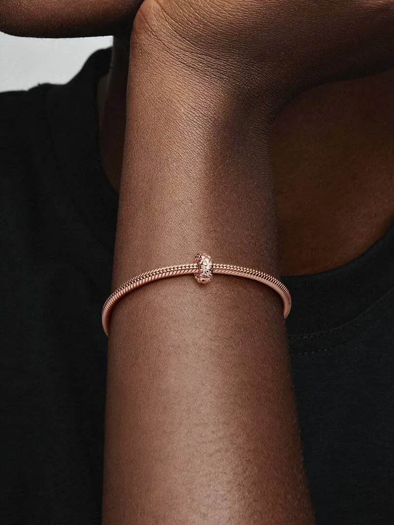 Gros plan du bracelet avec clip en or rose sur un poignet, vue latérale sur fond sombre.