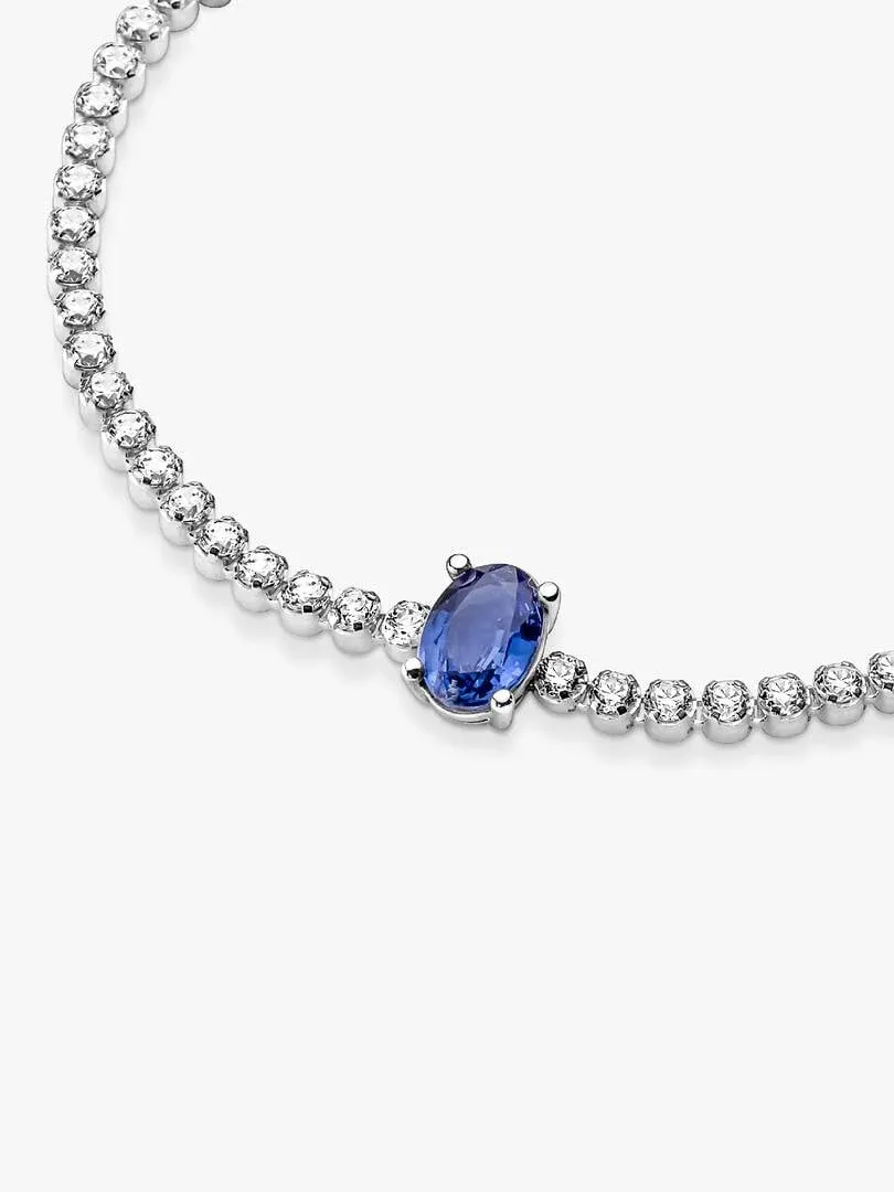 Primer plano de la pulsera con cristal azul ovalado y pavé, sobre fondo blanco.