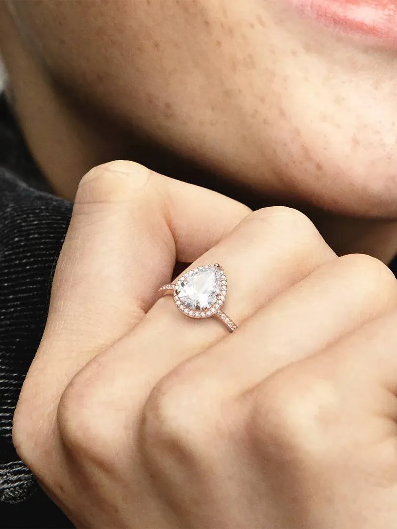 Close-up van de druppelring gedragen aan een vinger, zijaanzicht met wazige achtergrond.