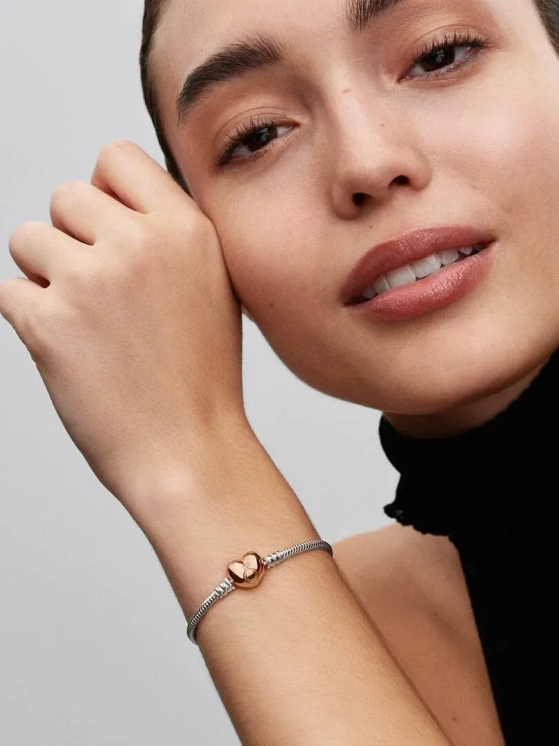 Primer plano de la pulsera en la muñeca, toma lateral con modelo sobre fondo gris neutro.