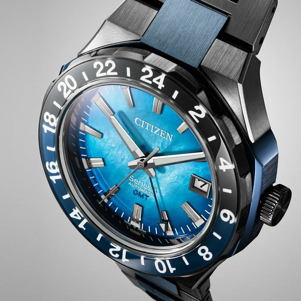 Primer plano en ángulo del dial azul texturizado y el bisel numerado sobre fondo gris neutro
