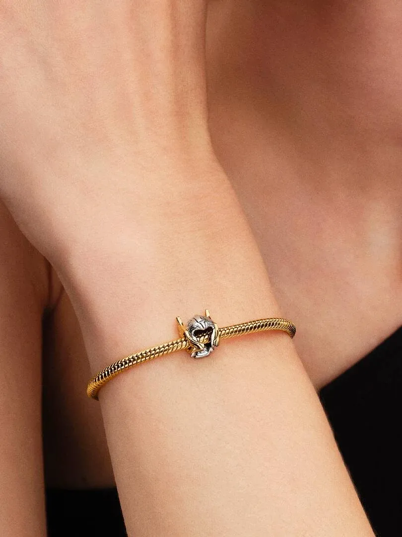 Gros plan du bracelet avec le charm casque de Thor sur un poignet, vue latérale sur fond sombre.