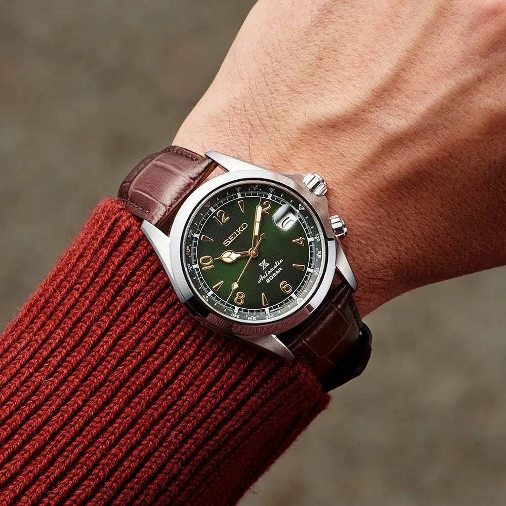 Reloj puesto en muñeca con jersey de punto rojo, toma en primer plano, fondo neutro desenfocado
