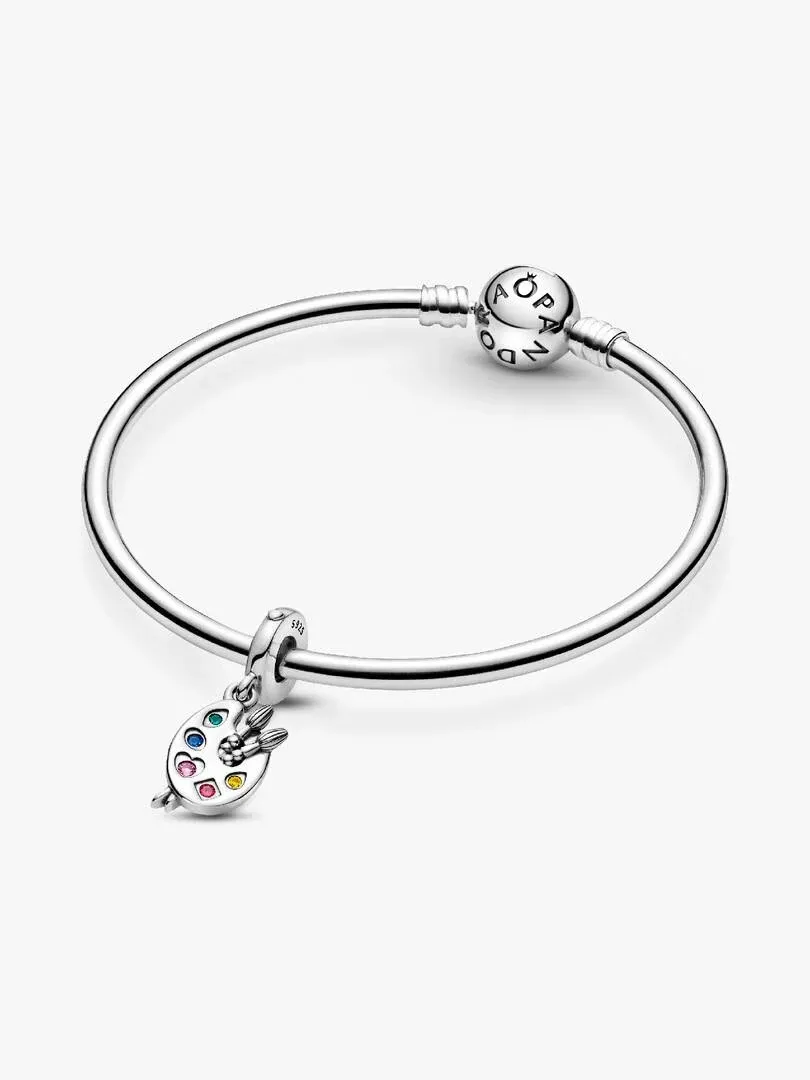 Pulsera de plata con charm de paleta de artista, vista en ángulo sobre fondo blanco.