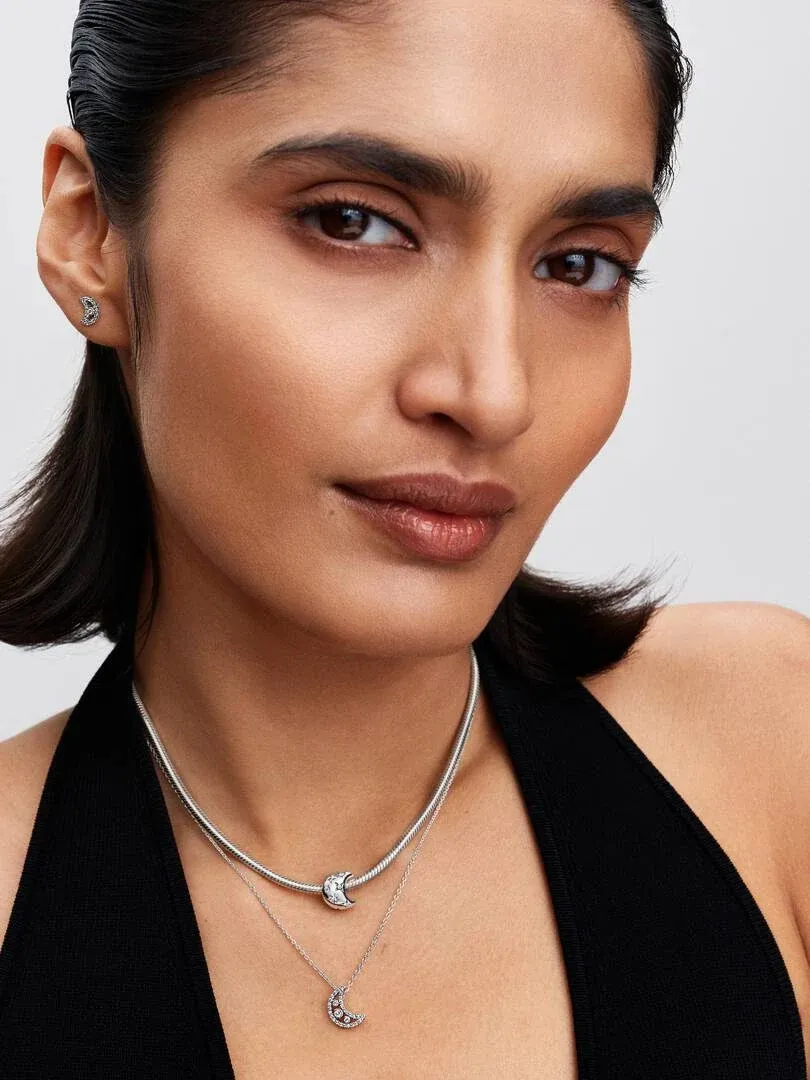 Primer plano de modelo con dos collares de plata, uno tipo gargantilla y otro con colgante de luna creciente.