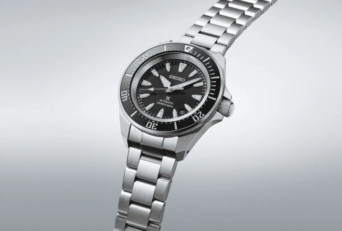 Vista en perspectiva del reloj completo sobre fondo gris degradado, destacando la caja y el brazalete de acero.