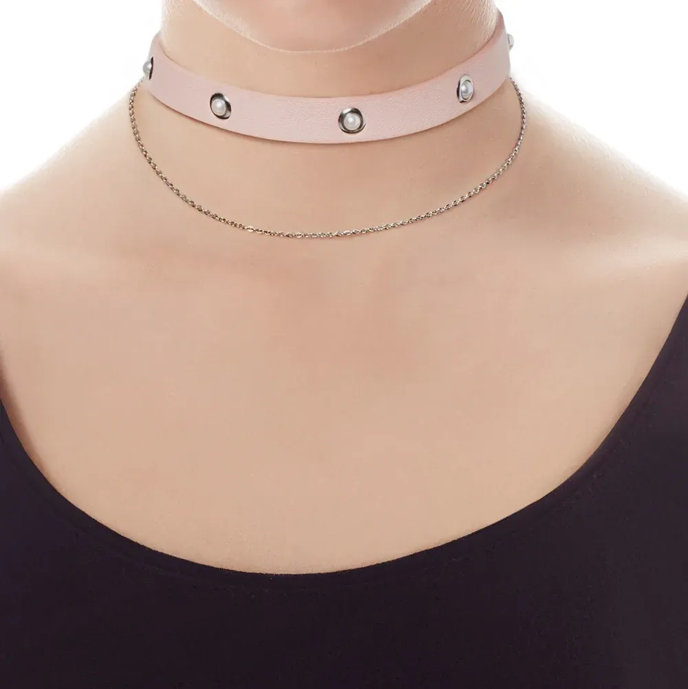 Gros plan du collier ras du cou rose avec perles sur le cou d'un mannequin, fond blanc.