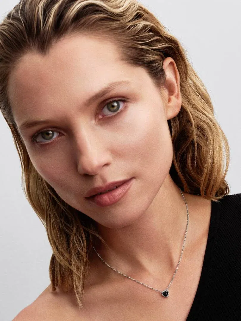 Gros plan d'un mannequin portant le collier cœur noir, vue de face du cou et du visage sur fond neutre.