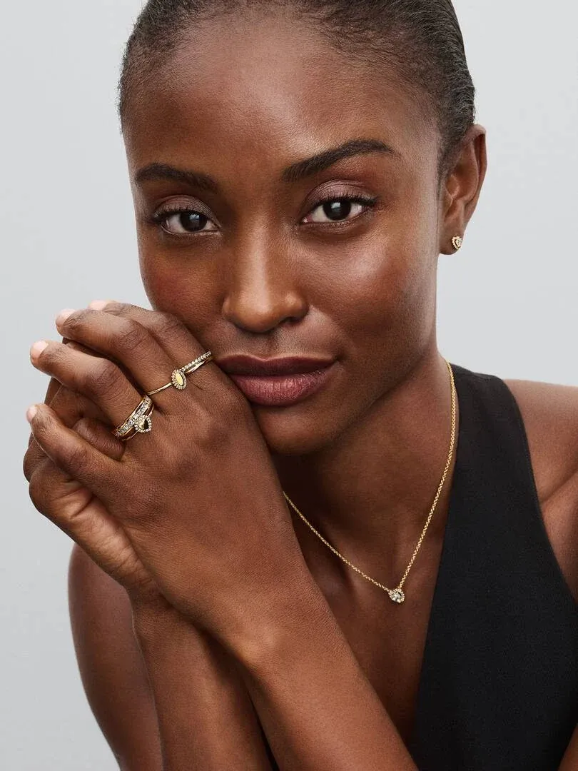 Primer plano de modelo con anillo de doble banda y collar, toma frontal sobre fondo gris neutro.