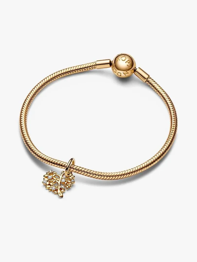 Charm de árbol en forma de corazón colgando de una pulsera de oro, vista frontal sobre fondo blanco.