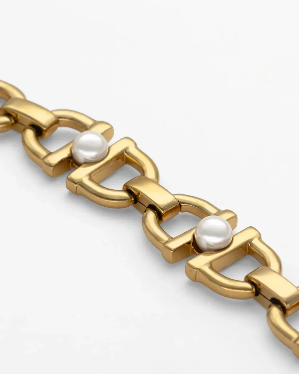 Diagonale Nahaufnahme der goldenen Glieder und weißen Perlen auf weißem Hintergrund.