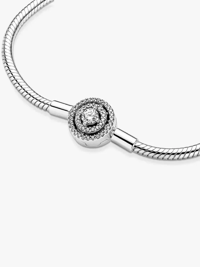 Primer plano del cierre circular con circonitas sobre cadena de serpiente, fondo blanco.