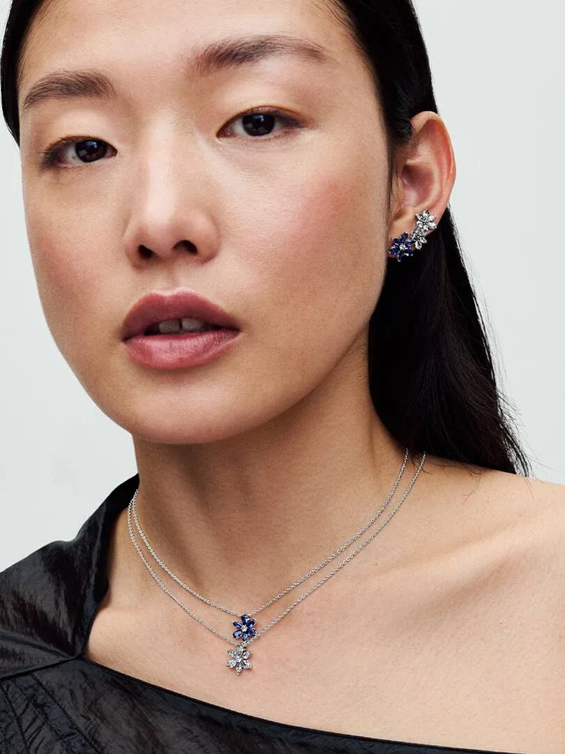 Gros plan d'un mannequin portant le collier et les boucles d'oreilles floraux, vue de face sur fond neutre.