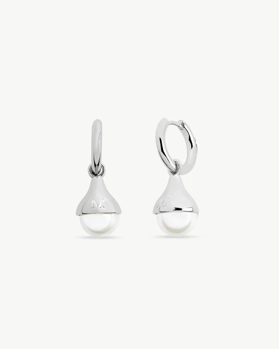 Paire de boucles d'oreilles créoles avec perle, vue de face sur fond blanc, détail du gravage argenté.