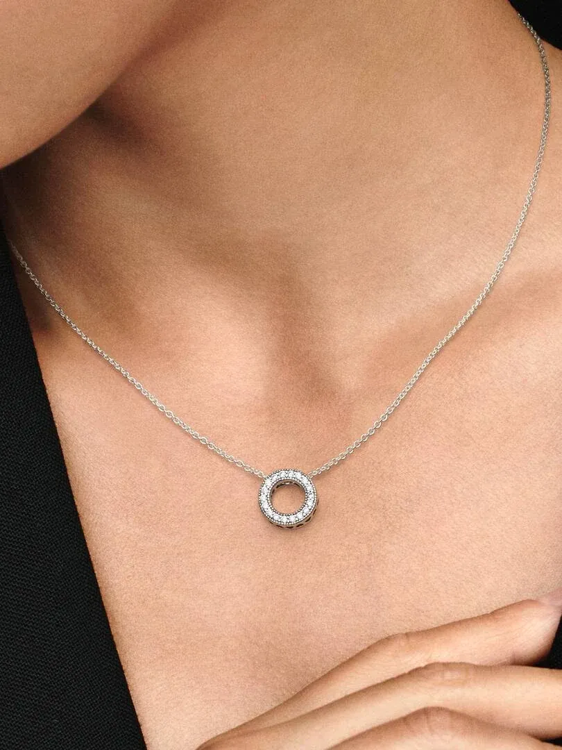 Primer plano del colgante circular de circonitas sobre el cuello de una modelo, toma frontal.