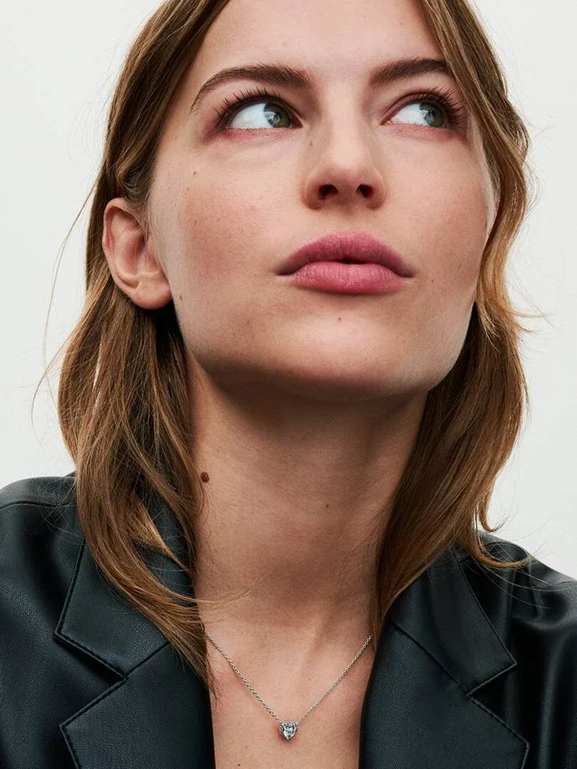 Gros plan du collier avec pendentif cœur sur le cou d'un mannequin, vue en contre-plongée, fond clair.