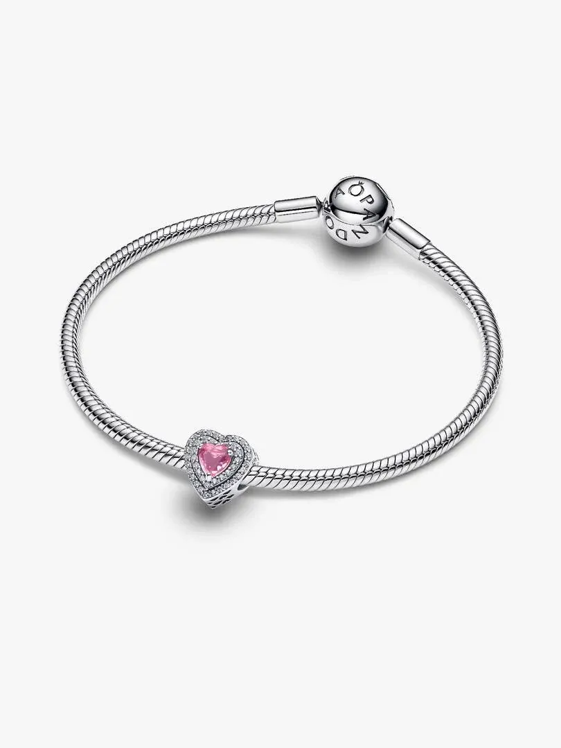 Charm de corazón rosa sobre brazalete de plata, vista frontal en ángulo, fondo blanco.