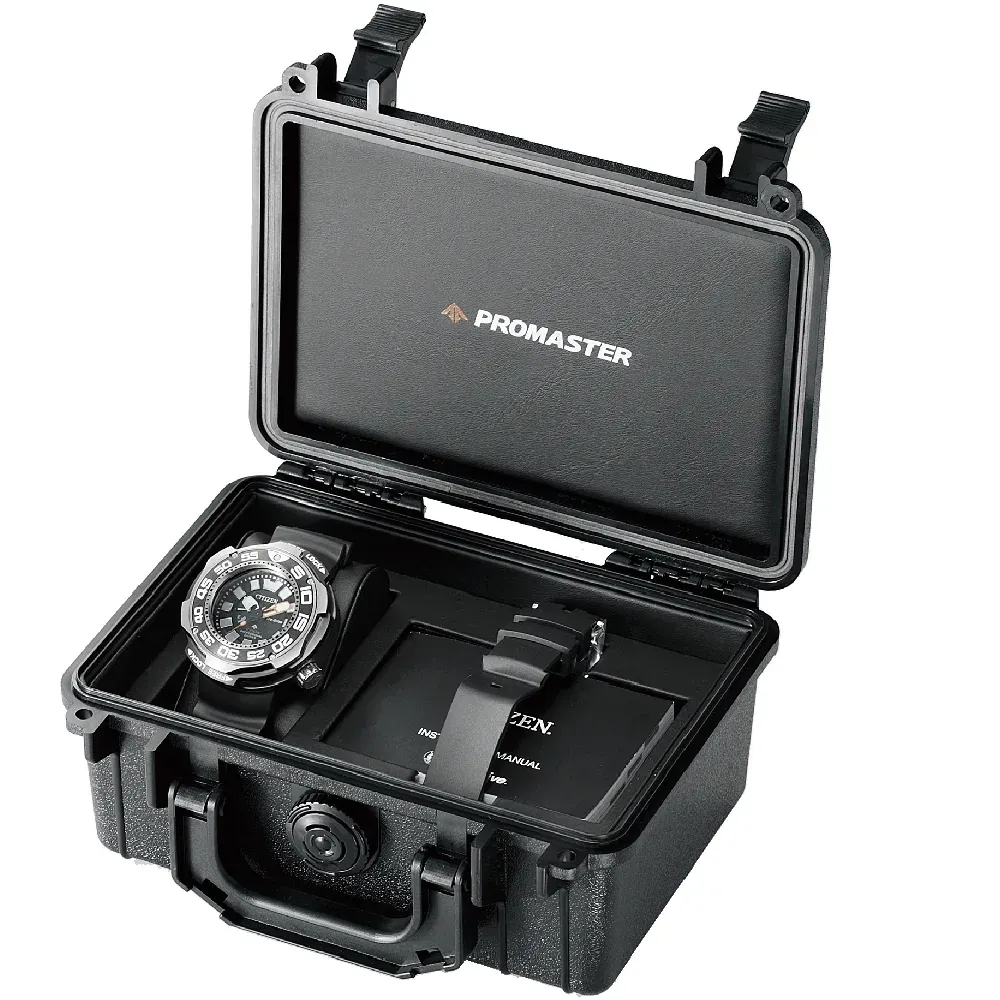 Estuche rígido de transporte negro abierto con logotipo Promaster, conteniendo el reloj y manual, fondo blanco.