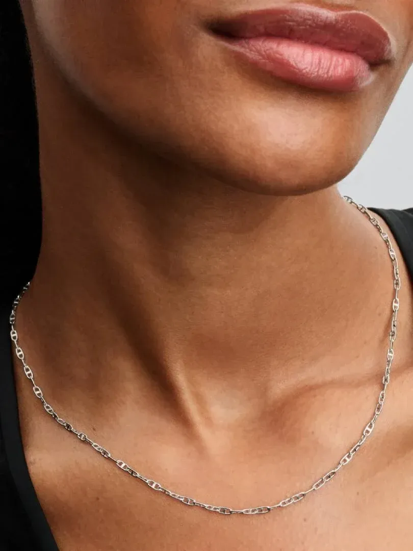 Primer plano del collar de plata sobre el cuello de una modelo, toma frontal con fondo neutro.