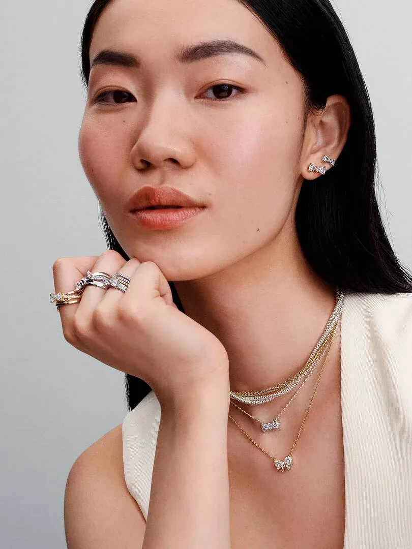 Gros plan d'un modèle portant un collier nœud et des boucles d'oreilles, vue de face.