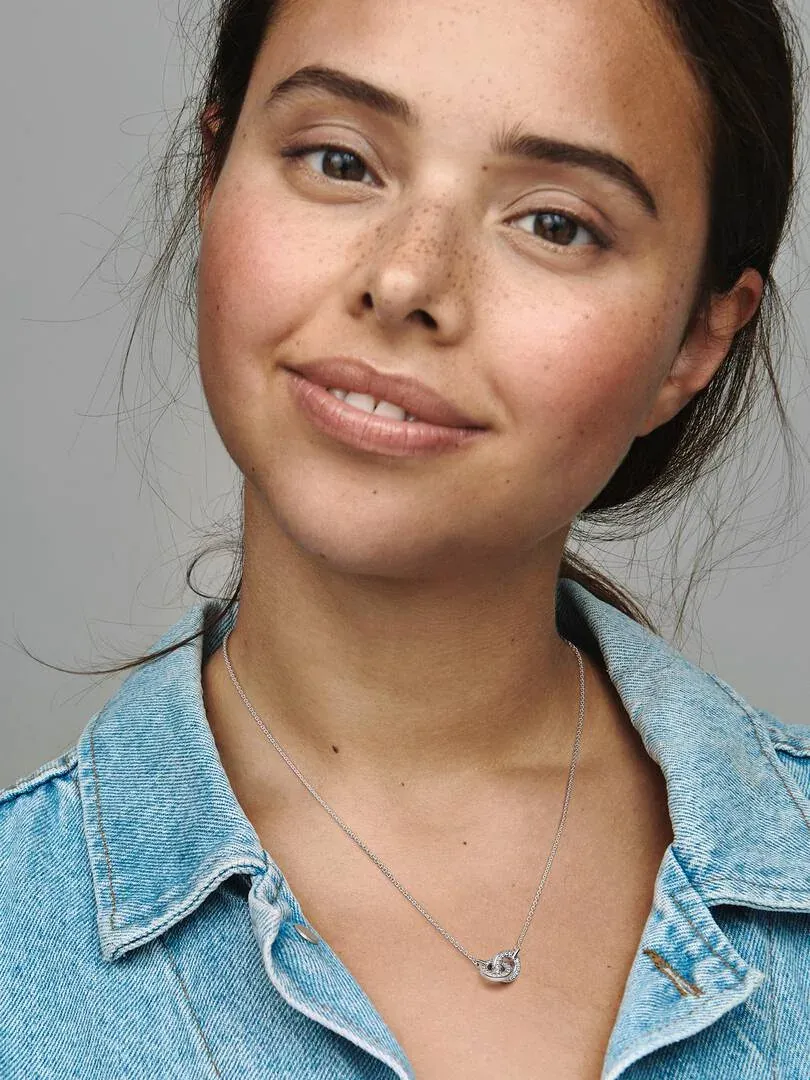 Gros plan du collier à cercles entrelacés en argent sur le cou d'un mannequin, chemise en jean.