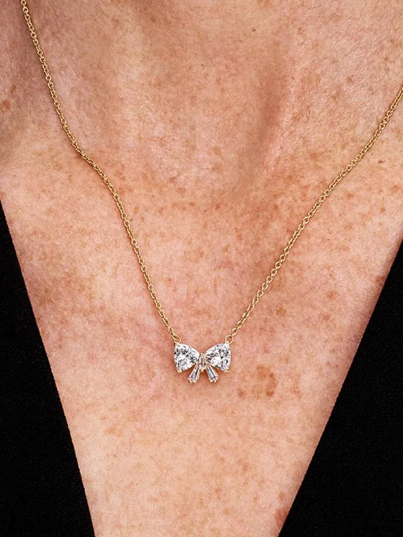 Close-up van de strik hanger op de hals van een model, vooraanzicht tegen een donkere achtergrond.