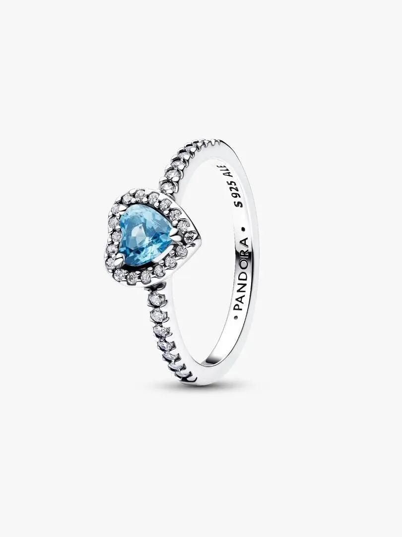 Anillo de corazón azul con halo de pavé, vista lateral en ángulo sobre fondo blanco.