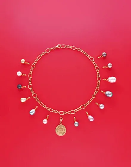 Collier à maillons dorés avec plusieurs breloques en perles, vue de dessus sur fond rouge vif.