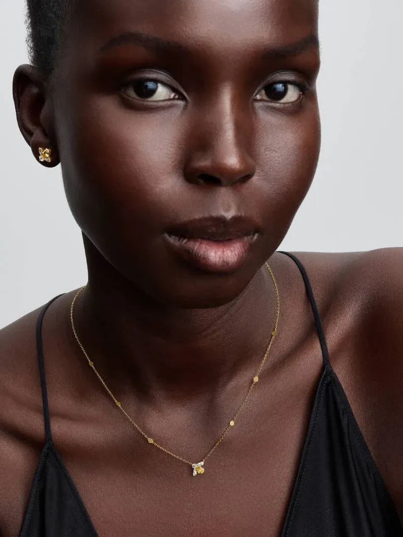 Gros plan du collier et boucles d'oreilles abeille portés par un modèle, vue de face sur fond neutre.