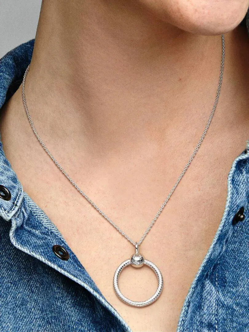 Primer plano del colgante circular de plata sobre el cuello y camisa vaquera de una modelo.