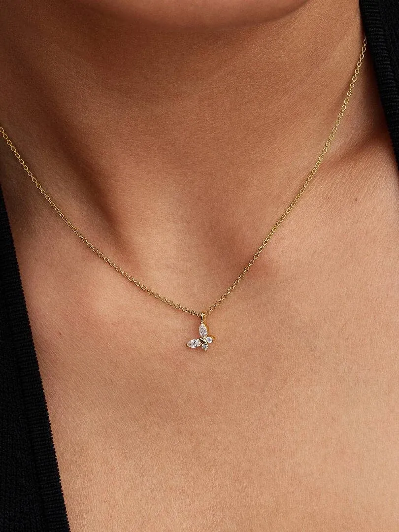 Gros plan du collier pendentif papillon sur le cou d'un mannequin, vue de face sur fond sombre.