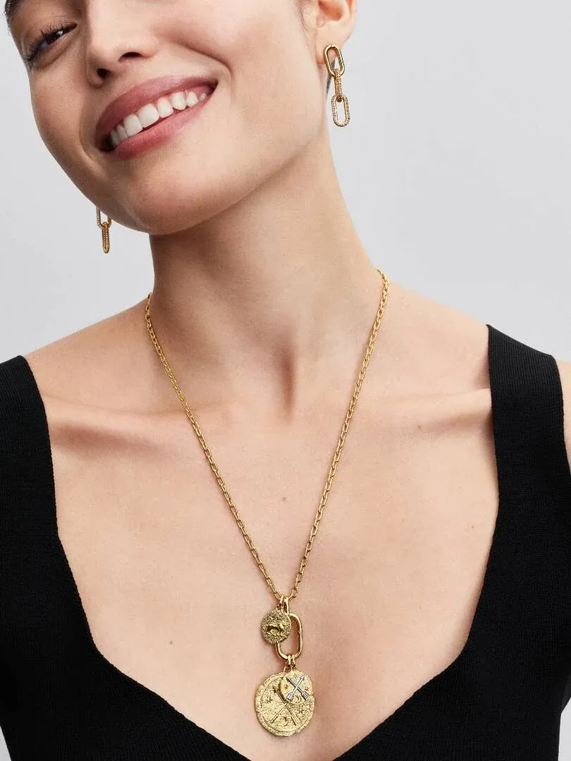 Gros plan d'un collier à médaillon doré sur le cou d'un modèle, fond neutre clair.