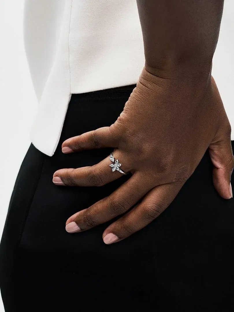 Close-up of the open ring with cubic zirconia worn on a finger, side view against black and white clothing.