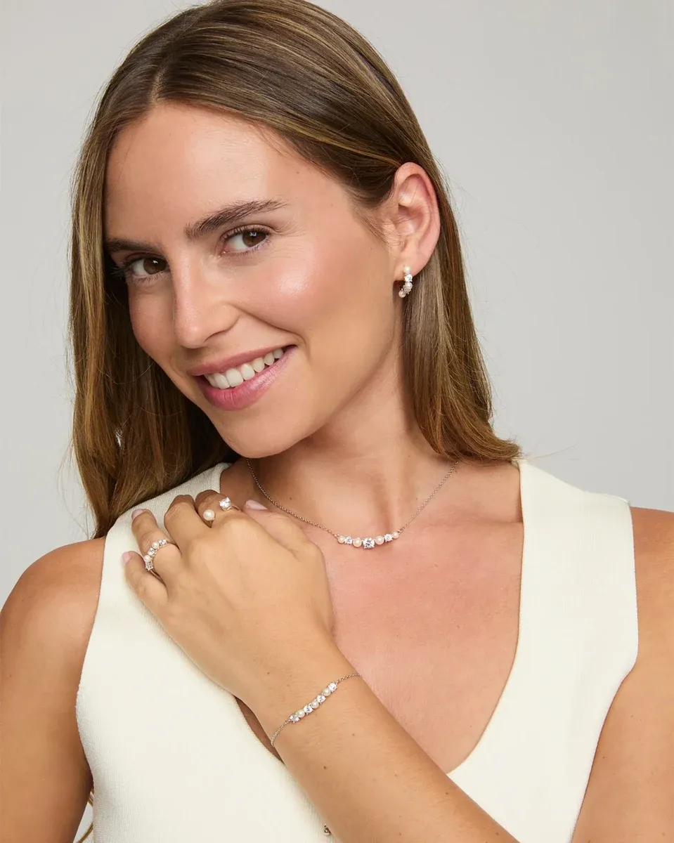 Modèle portant collier, boucles d'oreilles et bracelet en perles, plan moyen sur fond neutre.