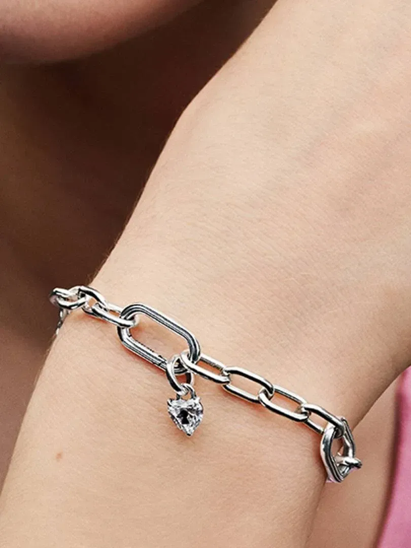 Primer plano de la pulsera con colgante de corazón sobre la muñeca, toma lateral en ángulo.