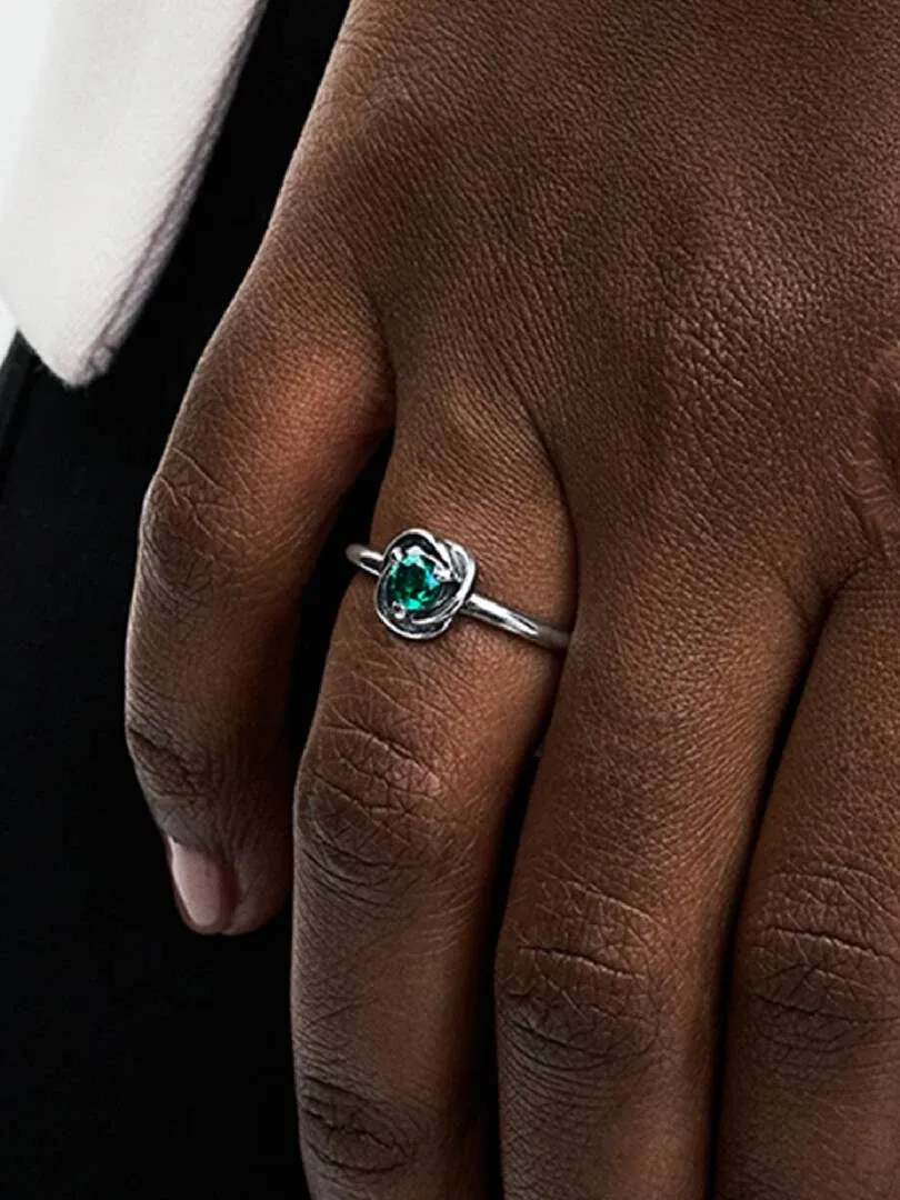 Close-up of the green gemstone ring on a ring finger, side view on skin.