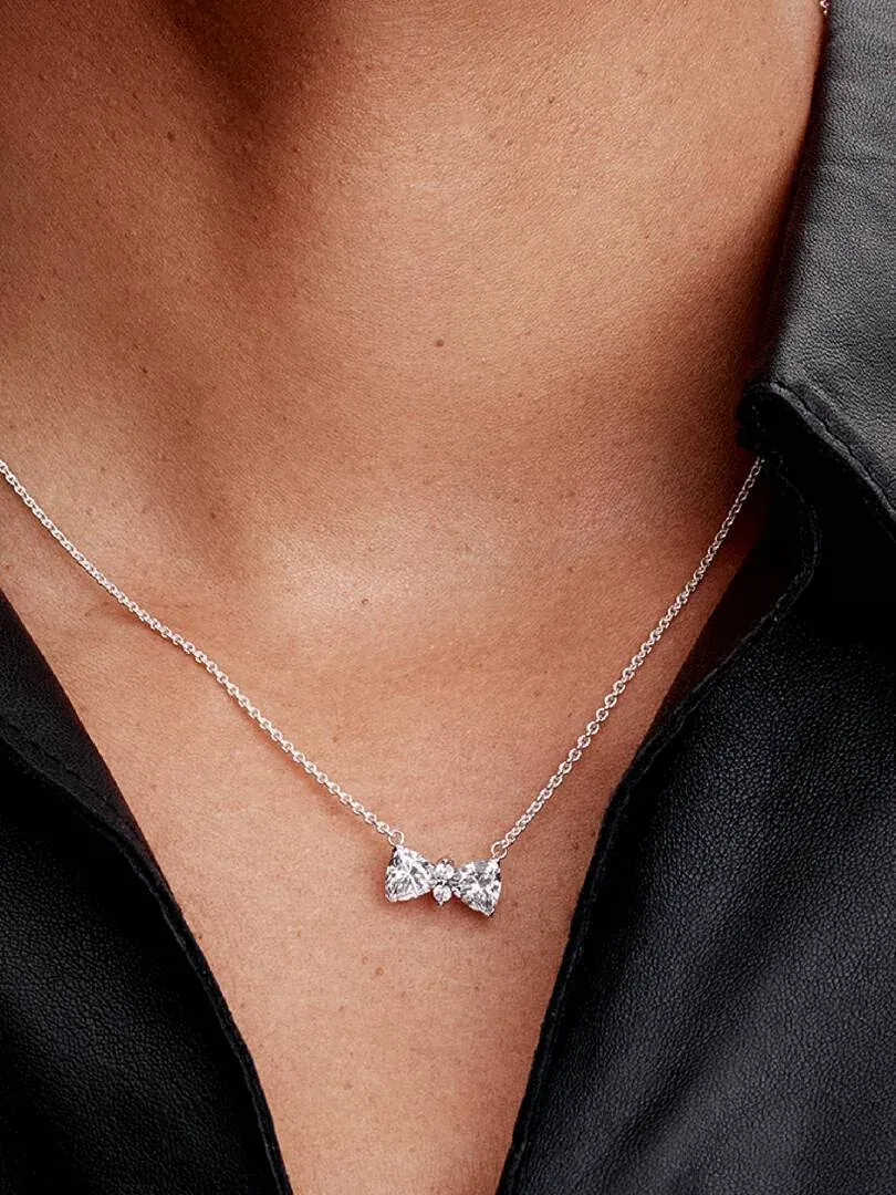 Gros plan du collier nœud avec zircons sur le cou d'un mannequin, fond sombre flou.