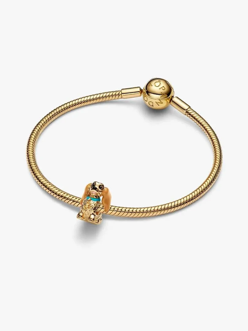 Charm de perrita sobre brazalete rígido dorado, vista frontal en ángulo, fondo blanco.