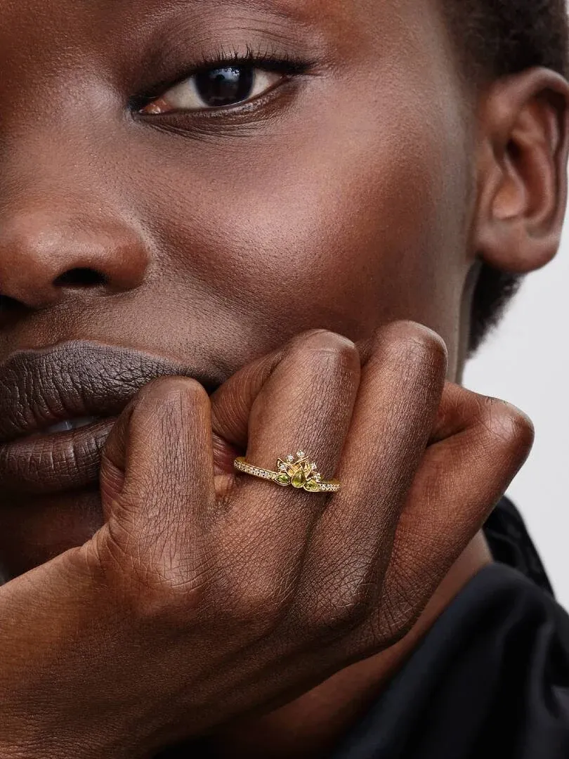 Primer plano del anillo con gemas verdes en el dedo, toma lateral sobre la mano de una modelo.