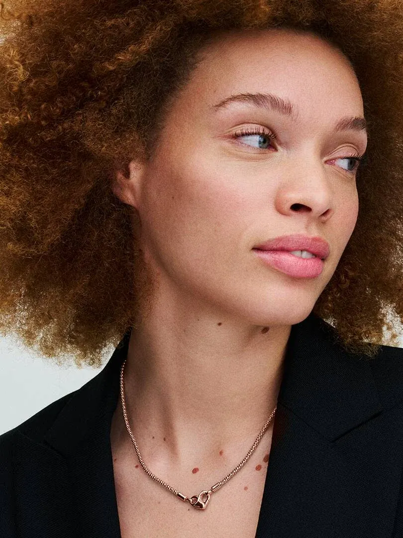 Primer plano del collar de oro rosa sobre el cuello de una modelo, toma frontal con fondo neutro desenfocado.